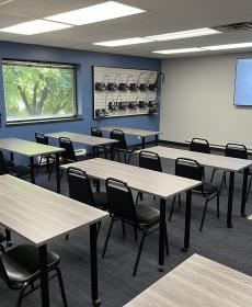 view of Chicago Faucets training room with tables and chairs and with slatwall faucet displays on the wall